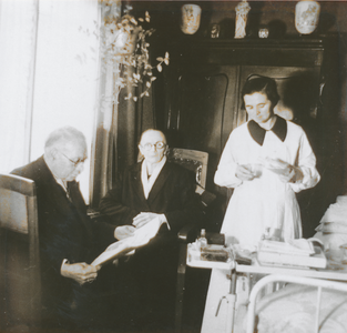 876920 Afbeelding van een Zuster Augustines (in opleiding?) die als gezinshulp werkt bij een bejaard echtpaar, ...